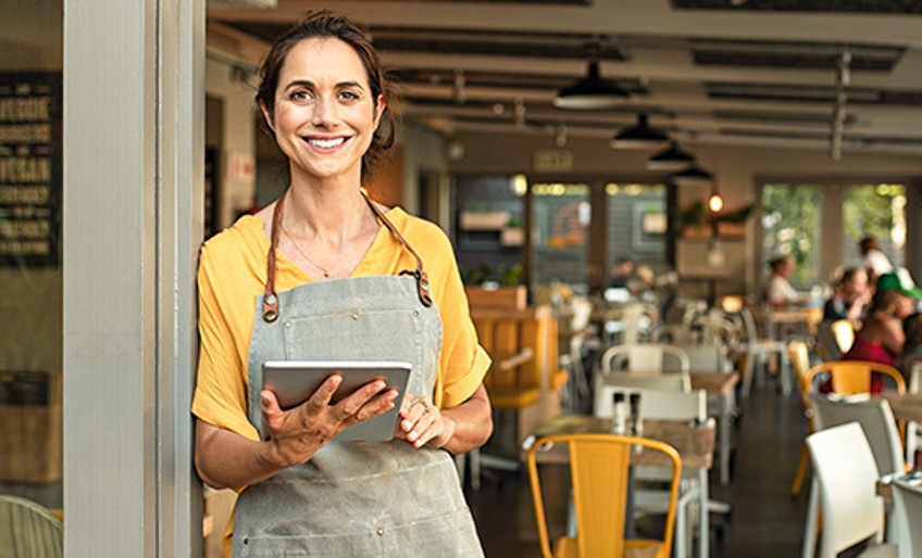 Betriebshaftpflichtversicherung – Café-Besitzerin mit Tablet in der Hand